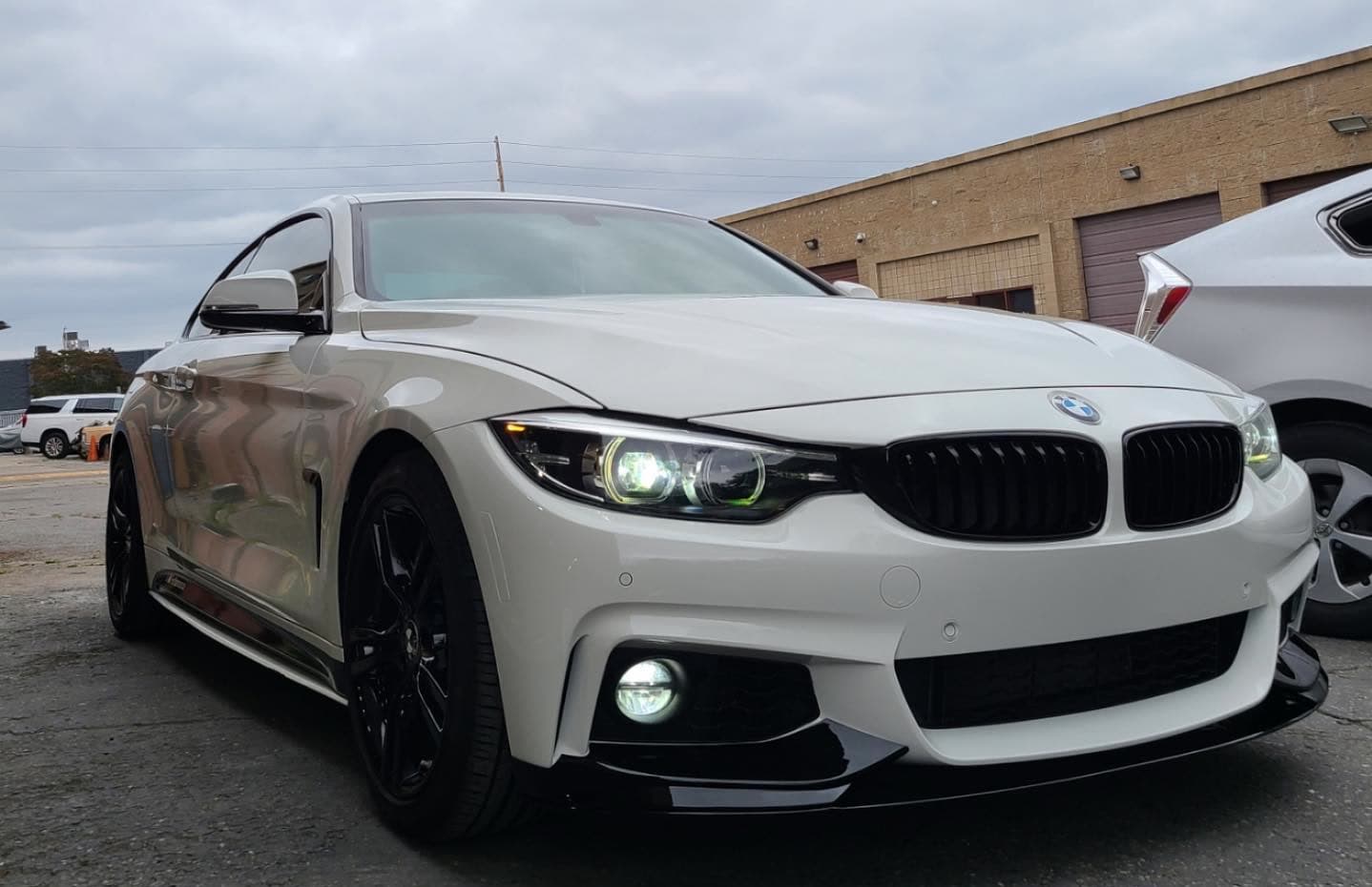 A white BMW 4-Series M Sport coupe parked in the shop's lot